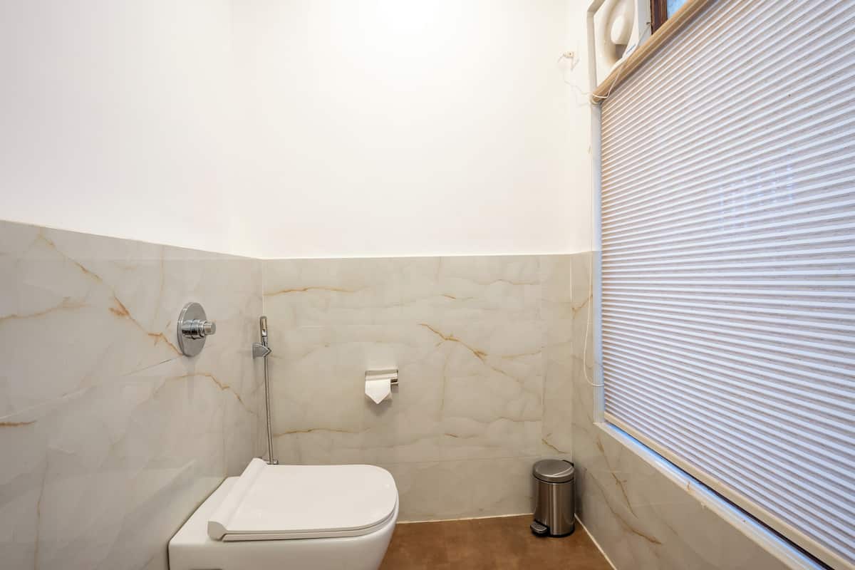 Un baño con inodoro, ducha y cubo de basura.