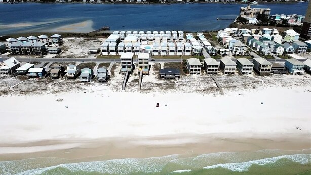 An aerial view of a coastal area with multiple beachside buildings, a sandy beach, and a body of water. - West Side Cottages B by Liquid Life (Gulf Shores)