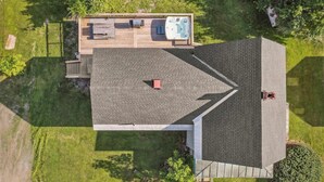 An aerial view of a house with a sloped roof, a hot tub, and a deck. - Serene 4-BR Farmhouse 5 min to Okemo (Ludlow)