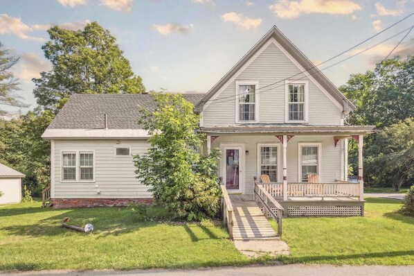 A two-story house with a front porch, a small front yard, and a visible chimney. - Serene 4-BR Farmhouse 5 min to Okemo (Ludlow)