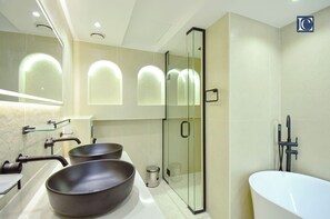 A modern bathroom with two large sinks, a glass-enclosed shower, and a white bathtub.