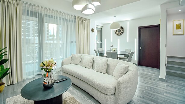 Een moderne woonkamer met een bank, salontafel en een eethoek met stoelen en een tafel.