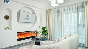 Een moderne woonkamer met een open haard, een bank, een salontafel en een groot raam met gordijnen.