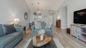 A modern living room with a sofa, coffee table, and TV stand. - Ironwood 1634 - Stunning Corner Unit! (North Myrtle Beach)