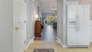 A hallway with a white refrigerator, a wooden cabinet, and a lamp. - Ironwood 1634 - Stunning Corner Unit! (North Myrtle Beach)