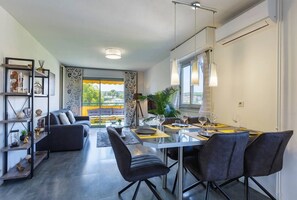 Un espace de salle à manger moderne, avec une table en verre, des chaises noires et une vue sur la ville grâce à de grandes fenêtres.