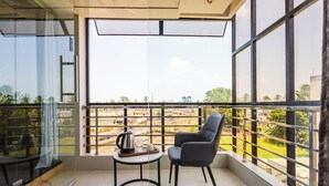 Ein Balkon mit Blick auf eine Stadtansicht, ein Tisch mit Kaffeekanne und Glas sowie ein moderner Stuhl.