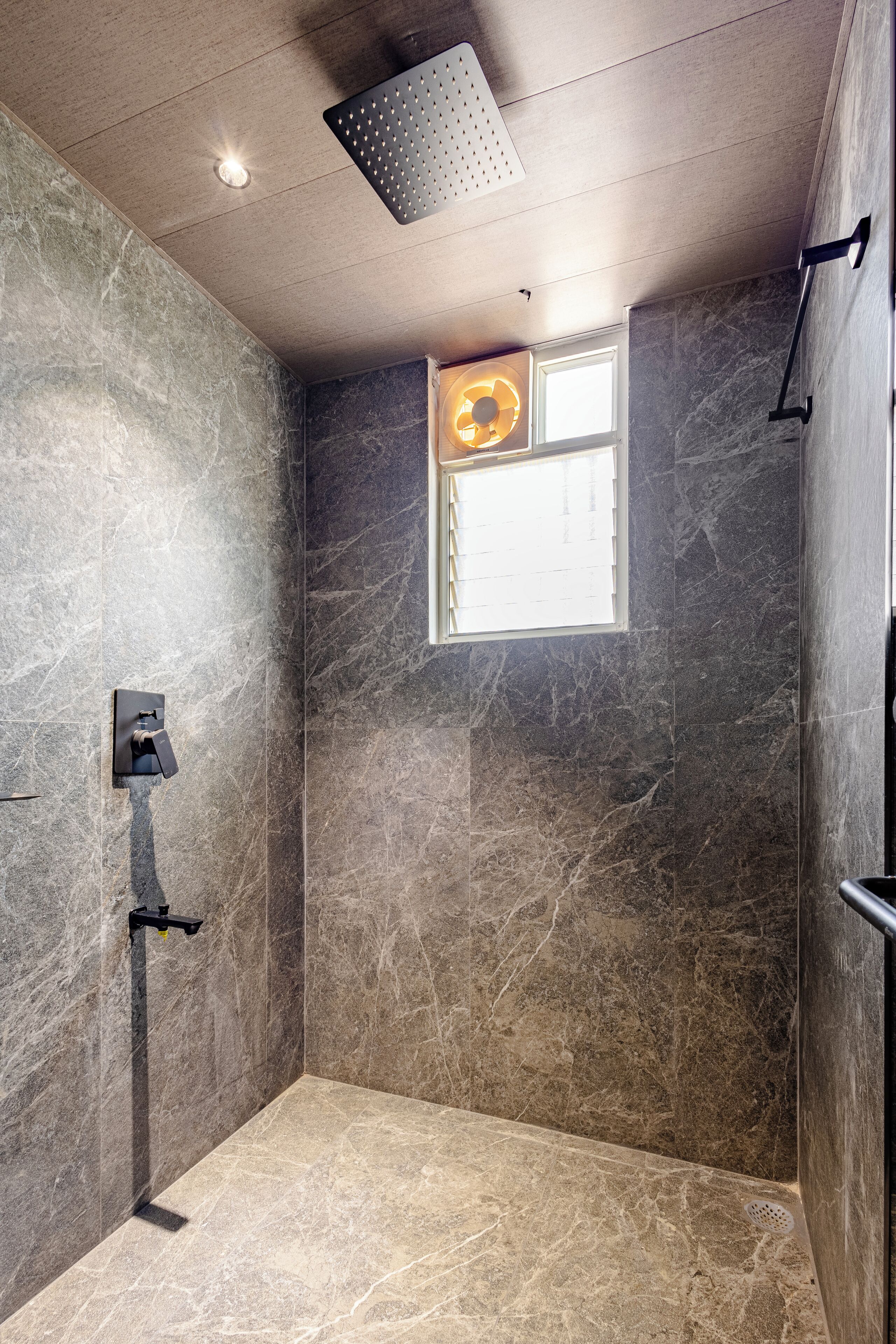 A modern bathroom with a shower, a window, and a built-in towel rack.