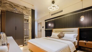 Ein modernes Hotelzimmer mit einem großen Bett, einem Nachttisch mit Lampe, einem Kleiderschrank und einem durchgegangenen Tür erkennbaren Badezimmer.
