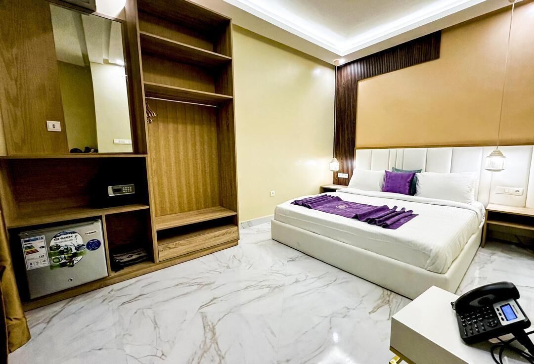 Une chambre d’hôtel comprenant un lit, une armoire, un bureau avec un téléphone et un petit coffre-fort.