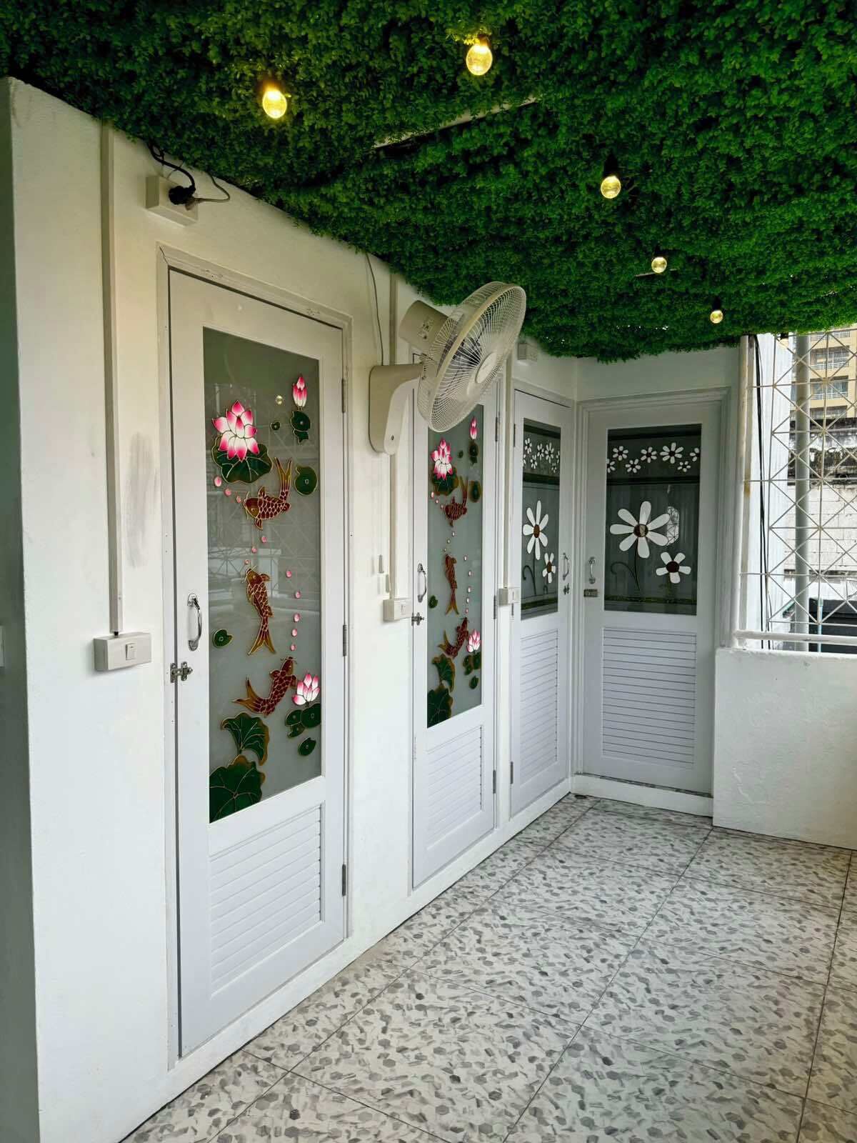 Corredor com portas brancas, cada uma decorada com painéis de vidro floral.