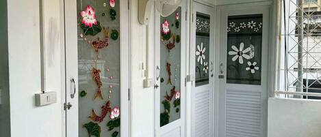 Un couloir aux portes blanches, chacune ornée de panneaux de verre décorés de motifs floraux.