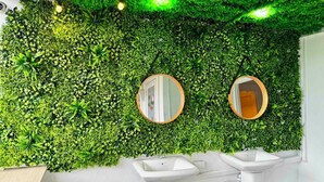 A bathroom with a green wall covered in foliage and two round mirrors. - Comfy Crib Hostel 2  (Bangkok)