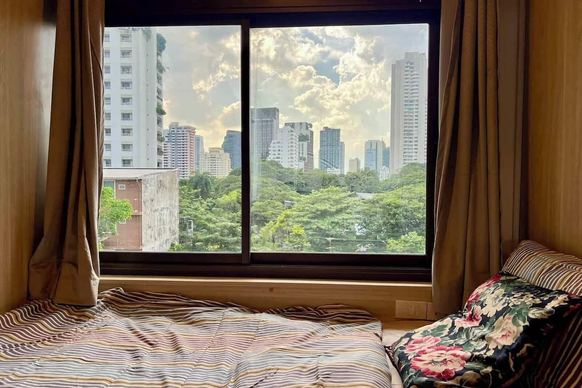 Un dormitorio con un ventanal que ofrece vistas a un paisaje urbano y zonas verdes.