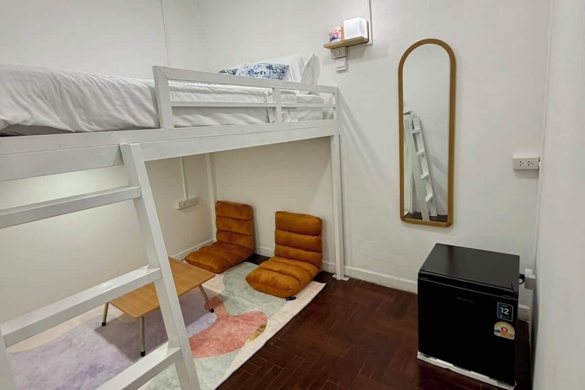 Habitación con literas, un escritorio pequeño, un espejo y aire acondicionado.