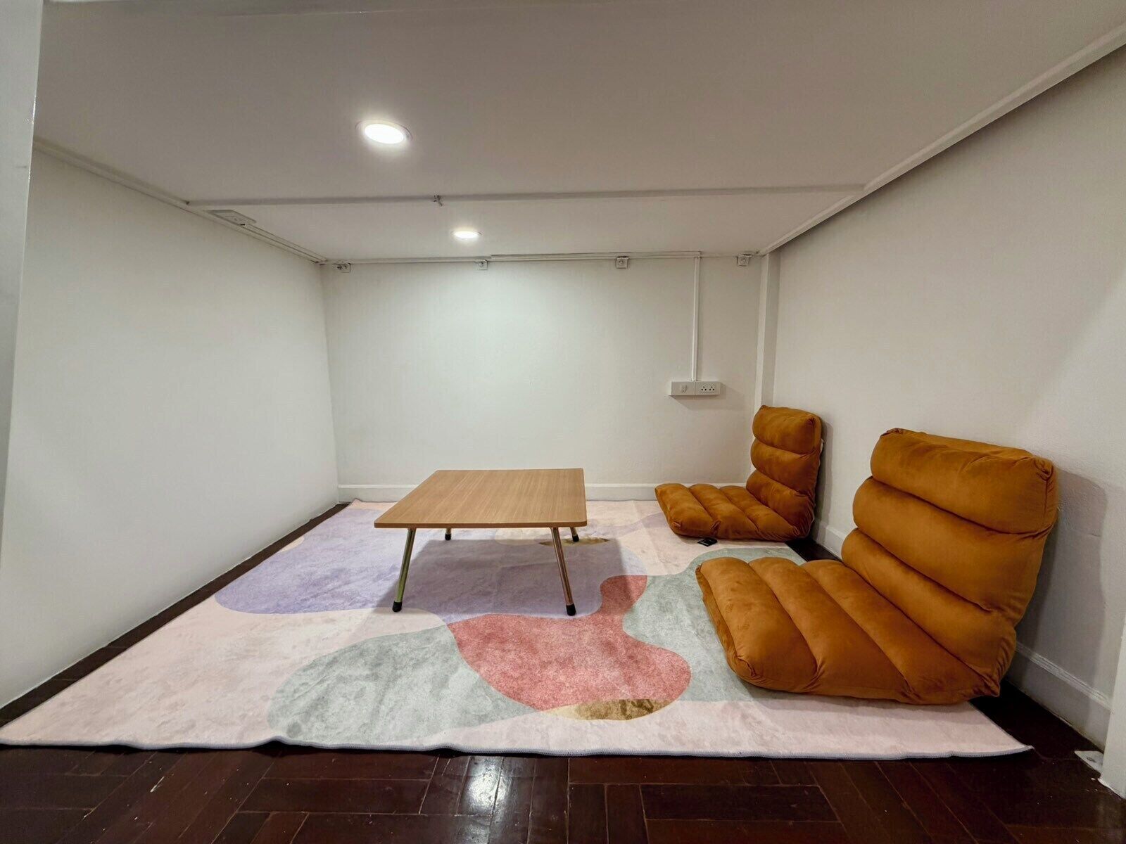 Une petite pièce, peu meublée, avec une table en bois et un grand fauteuil confortable.
