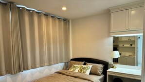 A bedroom with a bed, a desk, a chair, and a window with curtains. - Comfy Crib Hostel 2  (Bangkok)