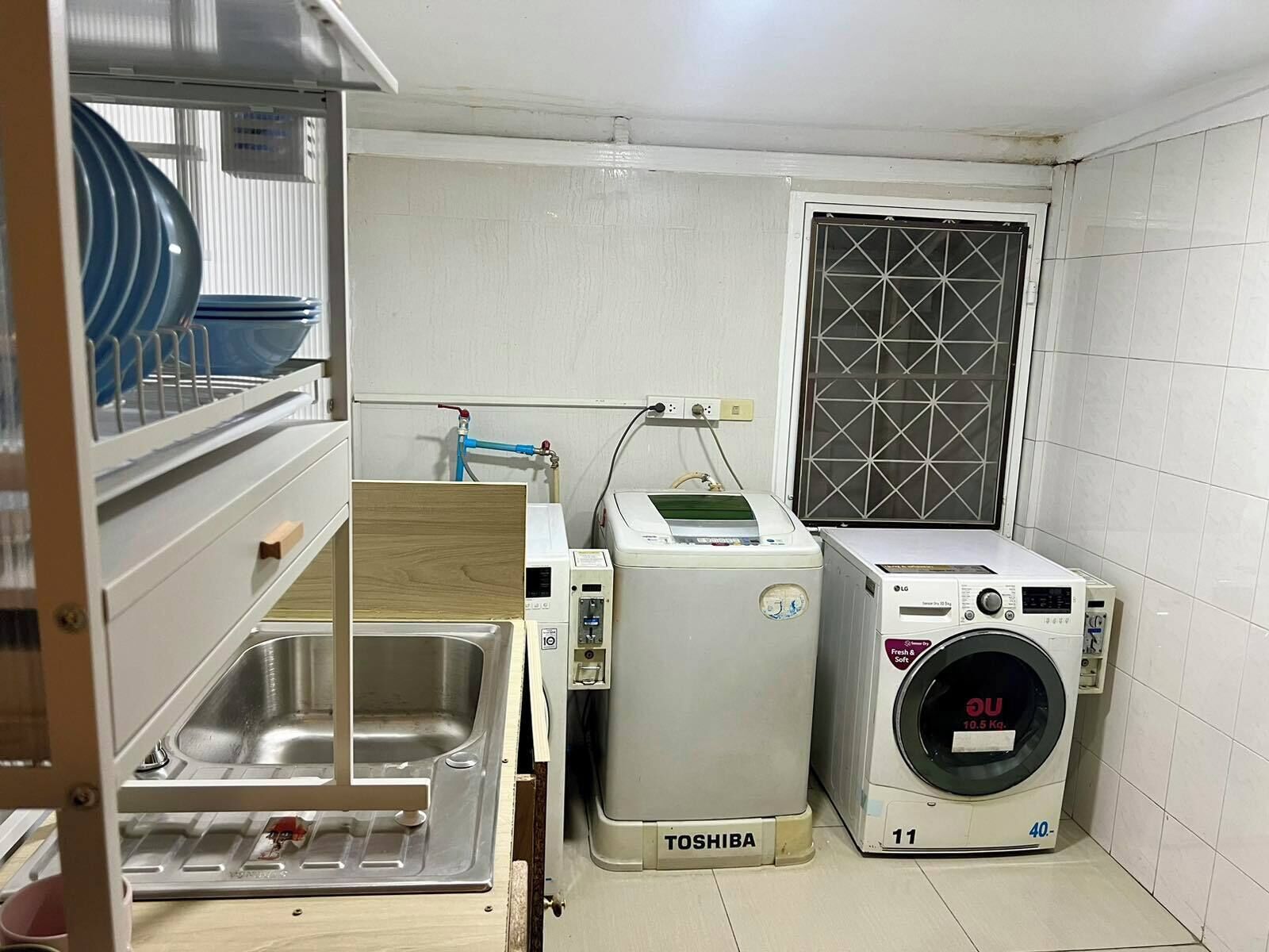 Un espace buanderie compact comprenant un lave-linge, un sèche-linge et un évier.