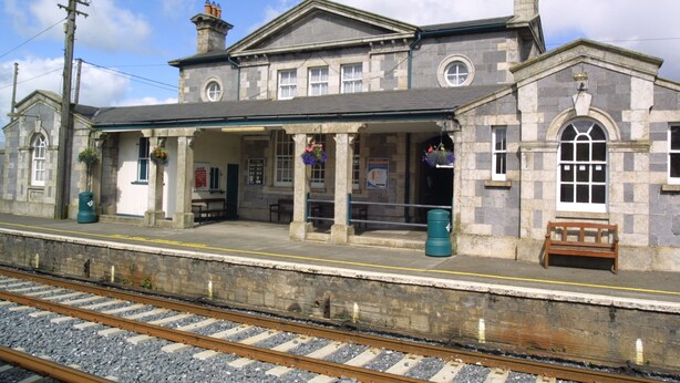 A stone building with a covered platform, benches, and a bench on the platform. - Mattys Pub & Apartments (Muine Bheag)