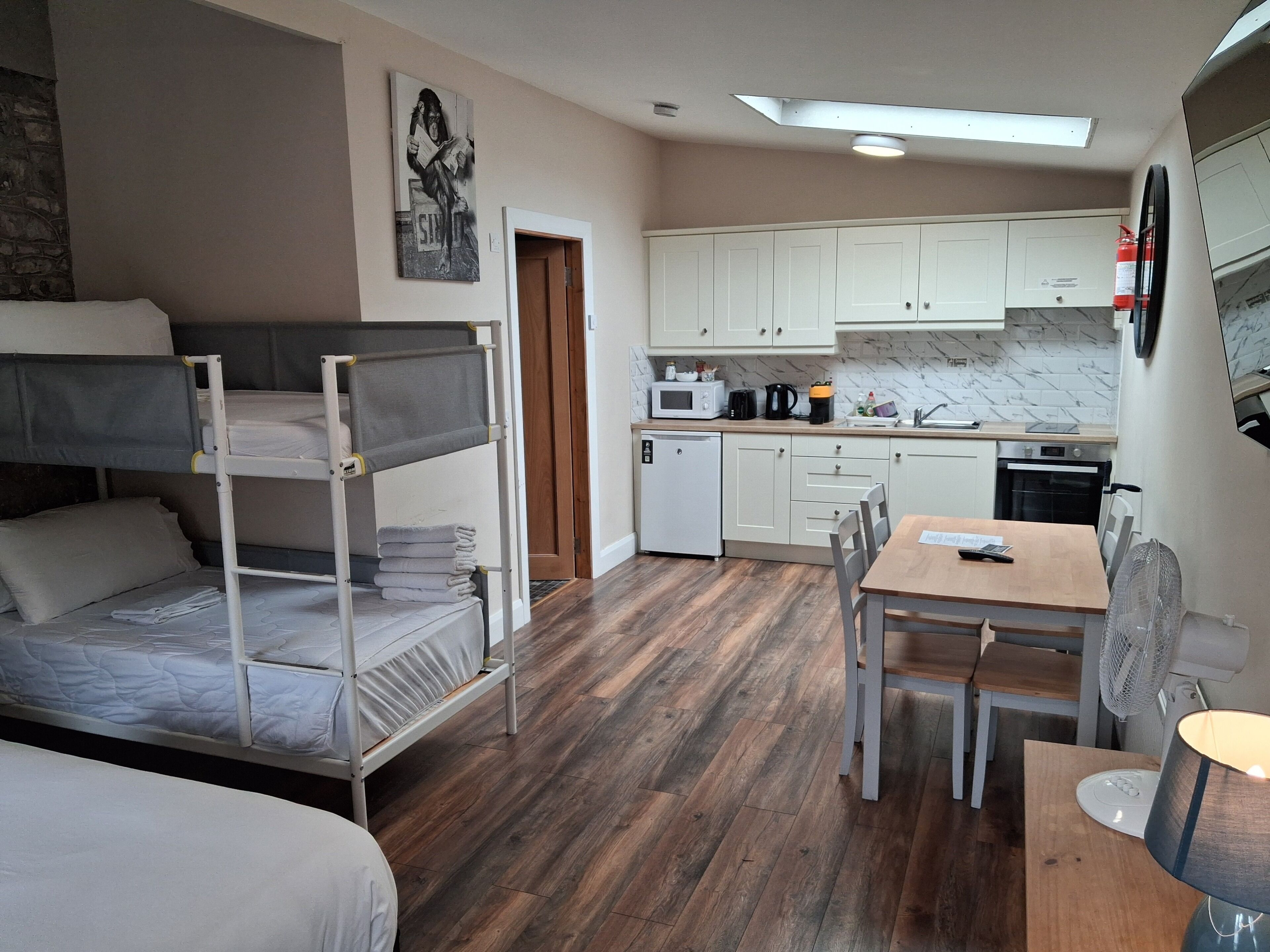 A compact room with bunk beds, a kitchenette, a dining area, and a small refrigerator.