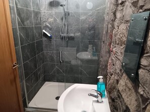 A bathroom with a glass-enclosed shower, a white sink, and a soap dispenser. - Mattys Pub & Apartments (Muine Bheag)