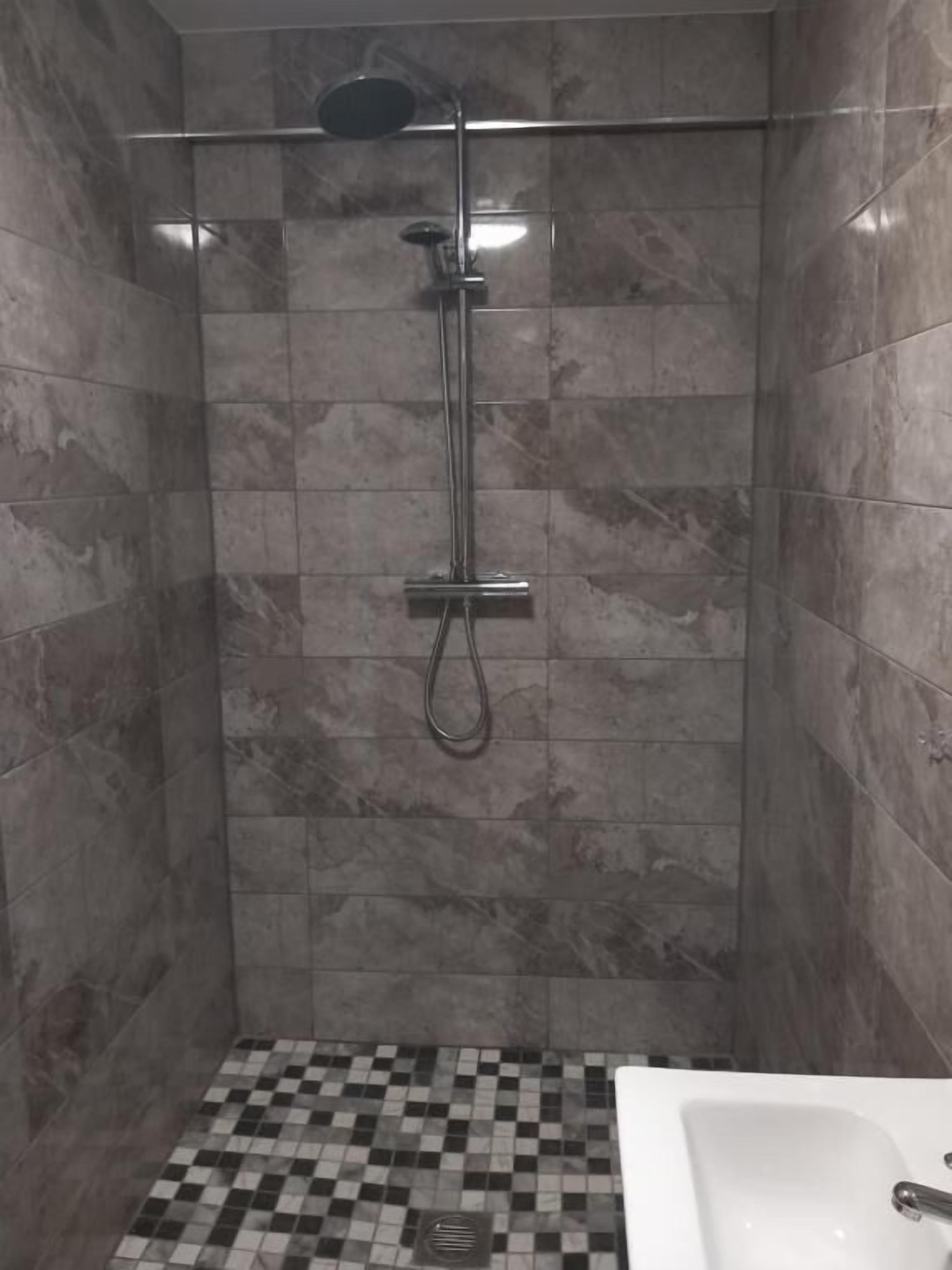 A shower with a glass door, a checkered floor, and a white sink.