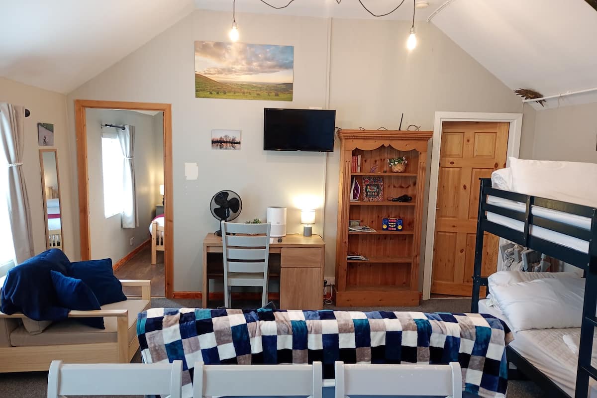 A cozy room with a bed, desk, chair, and a bookshelf.