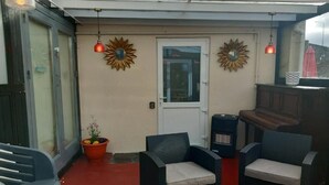Un espace extérieur aménagé en terrasse, avec des meubles en osier, une porte et des tournesols décoratifs.
