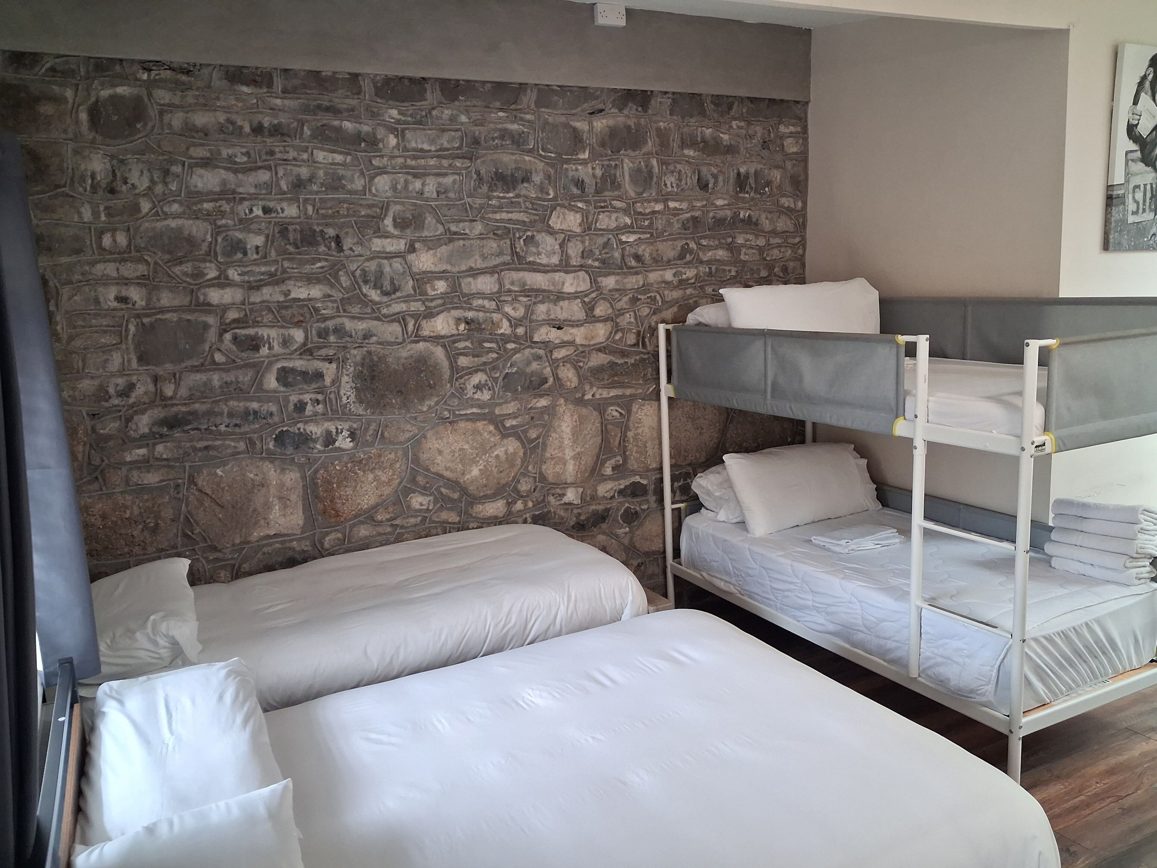 A room with bunk beds, a stone wall, and a painting on the wall.