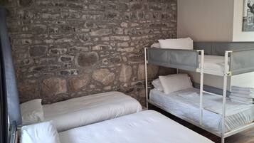 A room with bunk beds, a stone wall, and a painting on the wall.