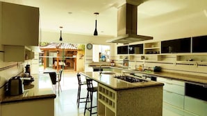 Cozinha moderna com ilha central, eletrodomésticos embutidos e área de refeições com banquetas de bar.
