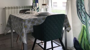 Een eethoek met een tafel gedekt voor twee personen, een stoel, een radiator en twee kunstwerken in lijsten aan de muur.