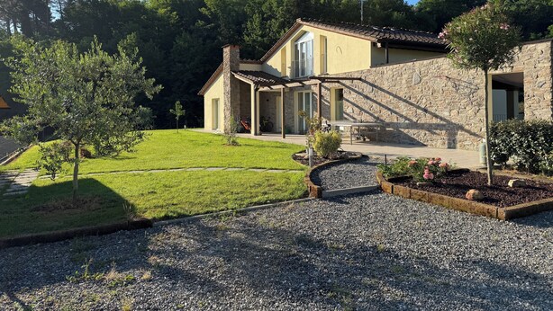 Uma casa de pedra com um pátio, um gramado e uma entrada com calçamento.