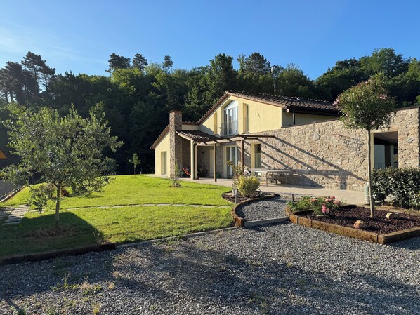 A stone house with a patio, a lawn, and a gravel driveway.