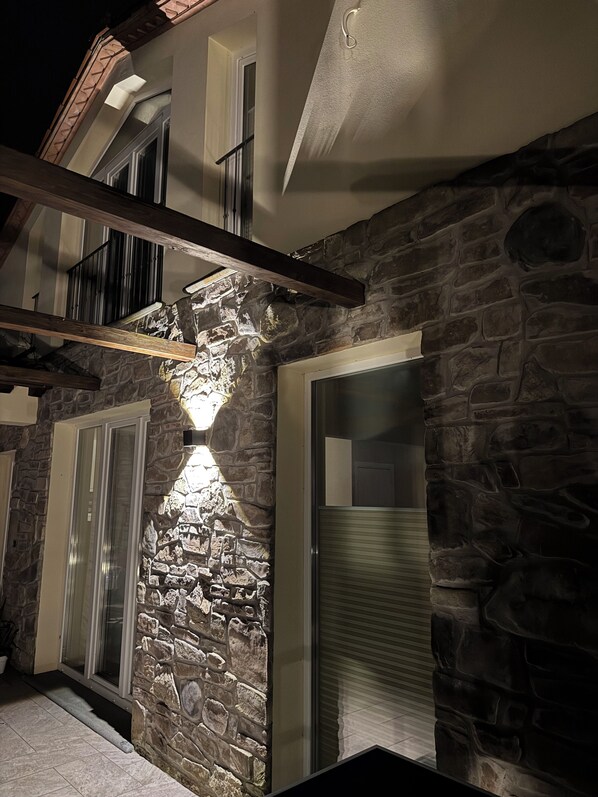 A stone facade with a balcony, a garage door, and a staircase leading to an upper level.
