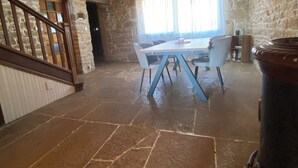 A spacious room with a stone floor, a wooden ceiling, and a dining area with a table and chairs. - Village house (9 pers), ideal for families, in the heart of the Jura mountains (Cesancey)
