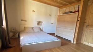 A bedroom with a wooden ceiling, a bed, a nightstand, and a wardrobe. - Village house (9 pers), ideal for families, in the heart of the Jura mountains (Cesancey)