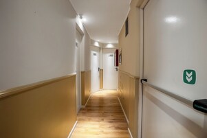 Un pasillo estrecho con suelo de madera, paredes blancas y puertas numeradas 501 y 504.