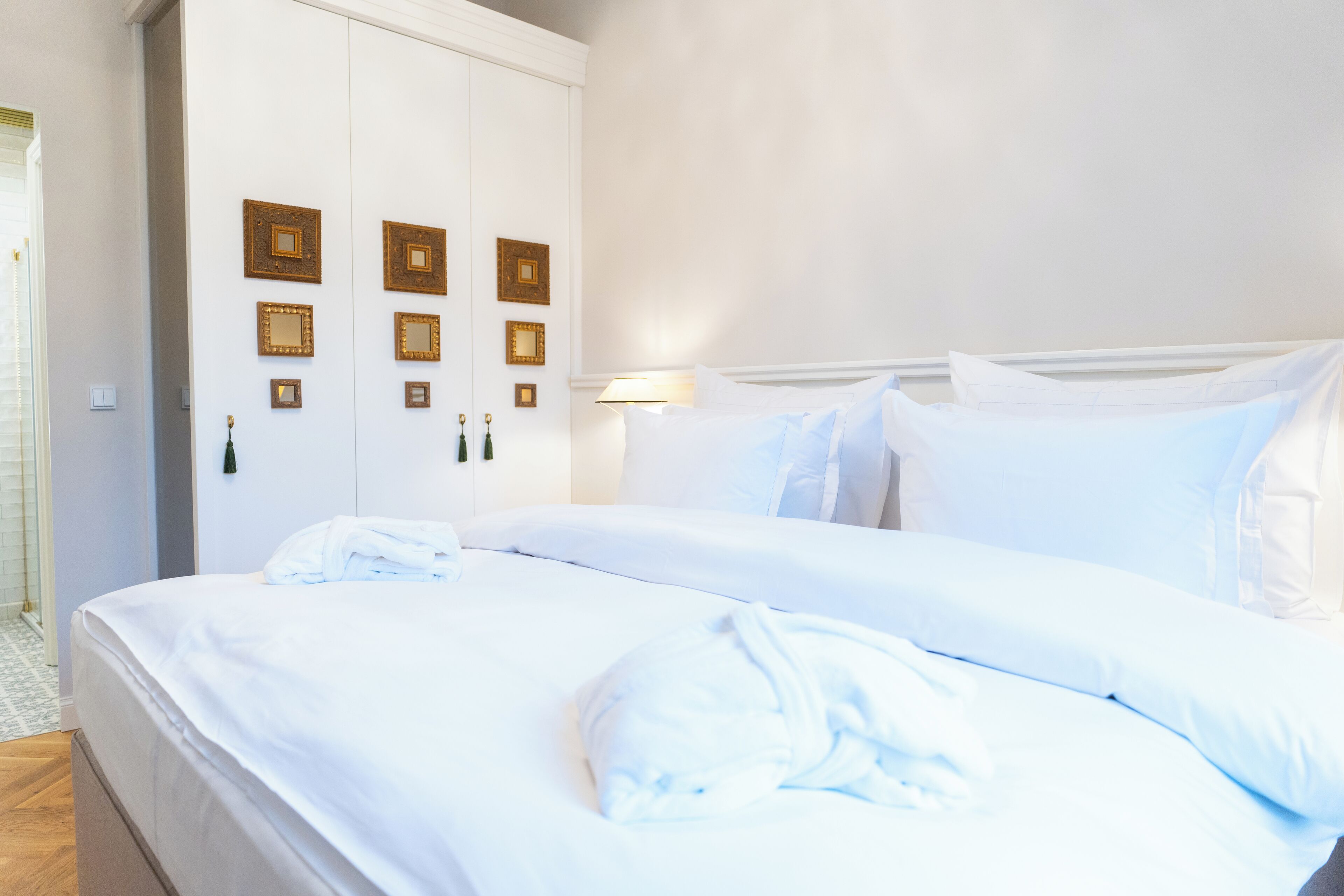 A hotel room with a large bed, a wardrobe, and wall-mounted mirrors.