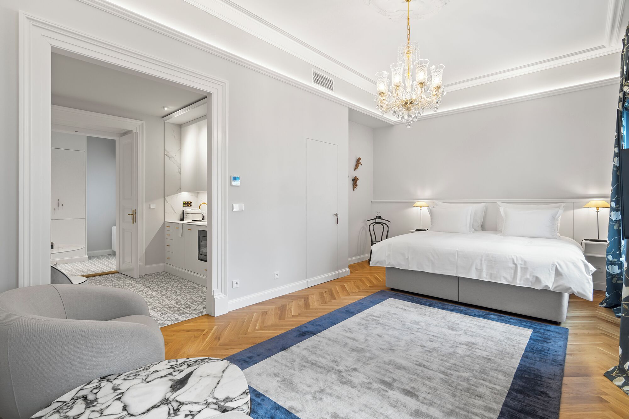 Un dormitorio moderno con una cama grande, una araña y vistas al pasillo.
