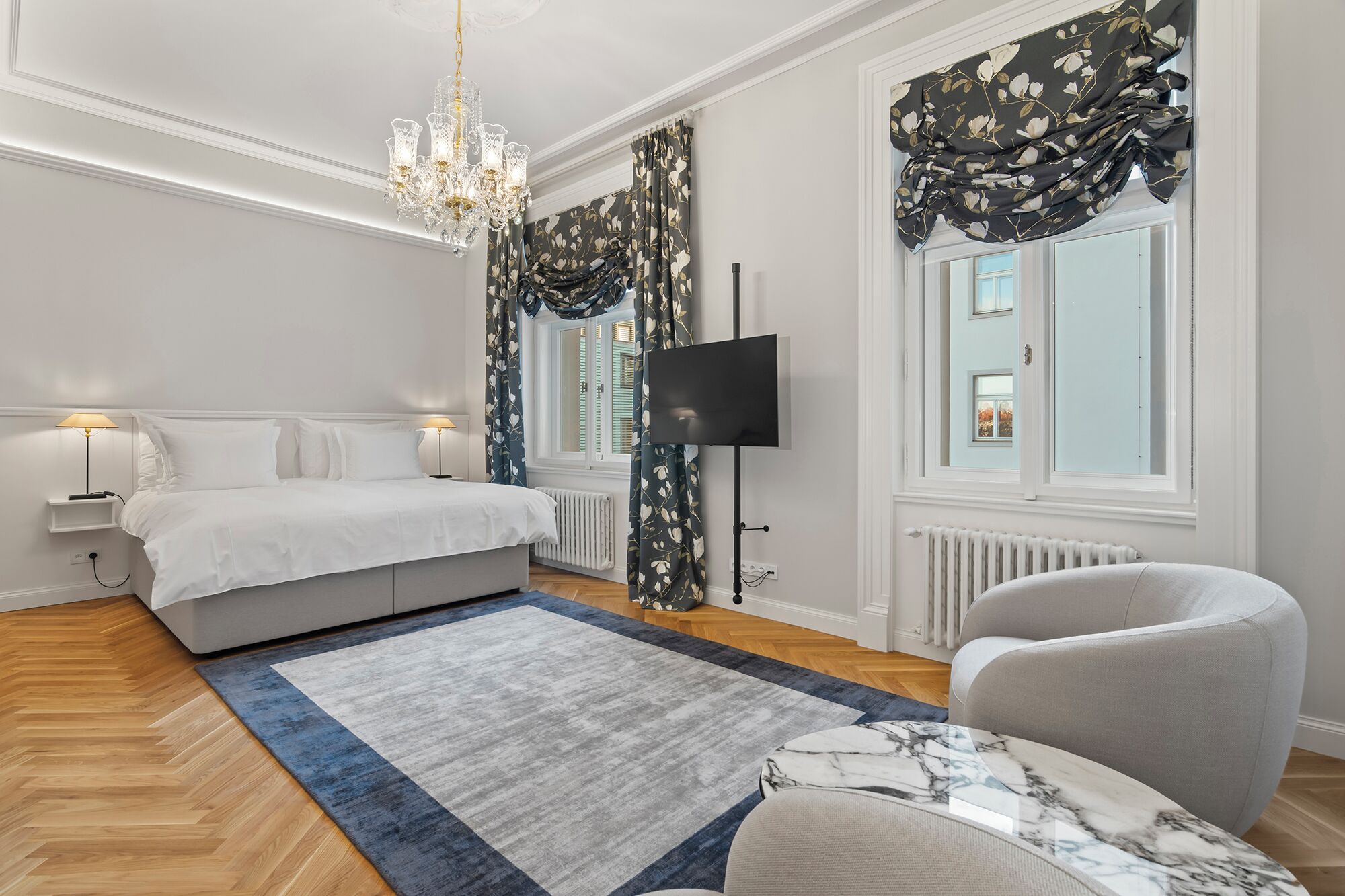 Une chambre à coucher moderne avec un lit, une chaise, un téléviseur et un lustre.