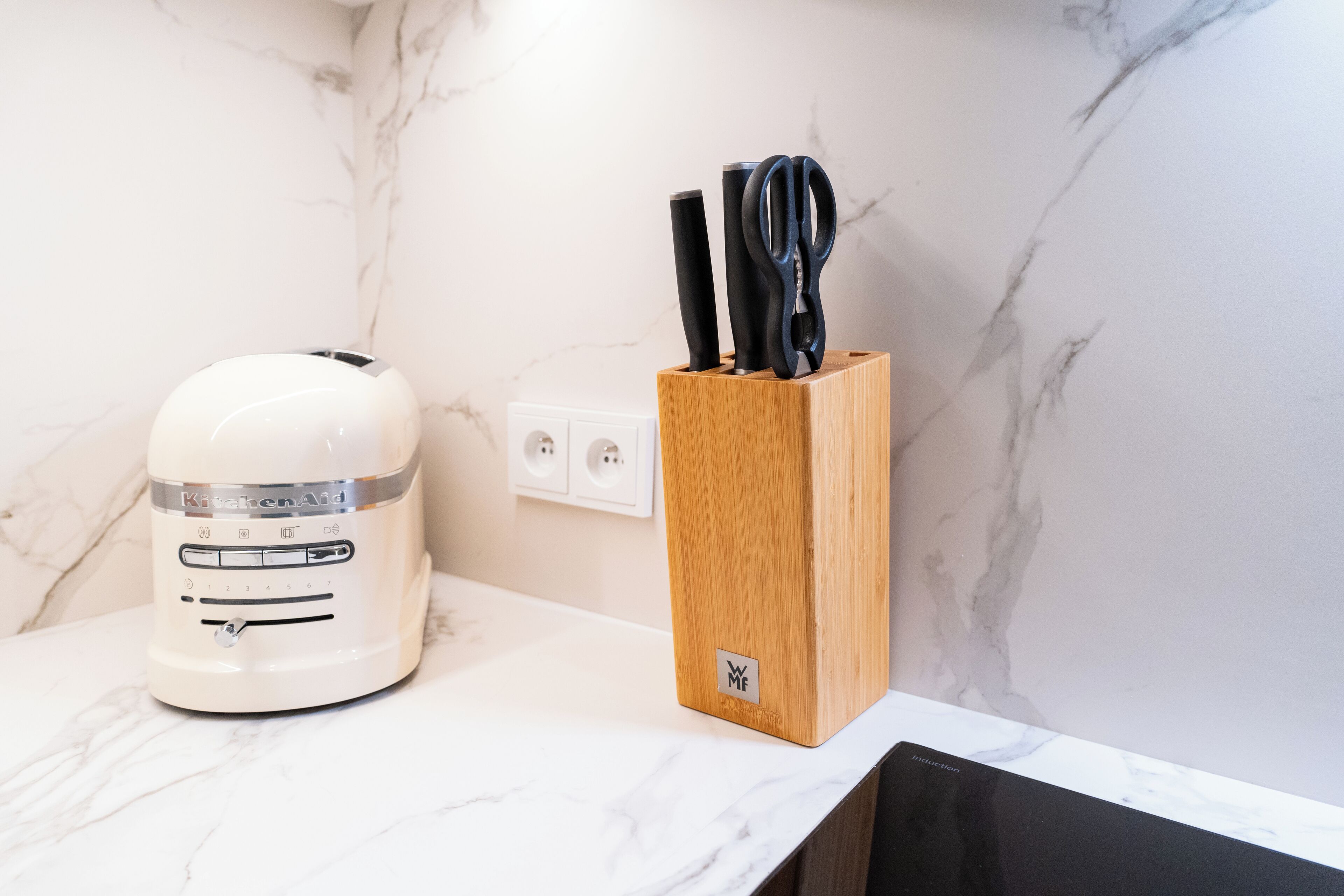 Een keukenblad met een witte KitchenAid mixer en een houten messenblok.