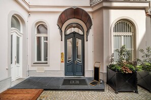 A building entrance with a dark blue door, a small black mat with the number 33, and a potted plant to the right. - Vodičkova Luxury Suites (Prague)