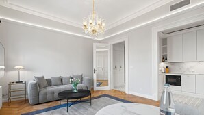 A modern living room with a grey sofa, a round coffee table, and a chandelier. - Vodičkova Luxury Suites (Prague)