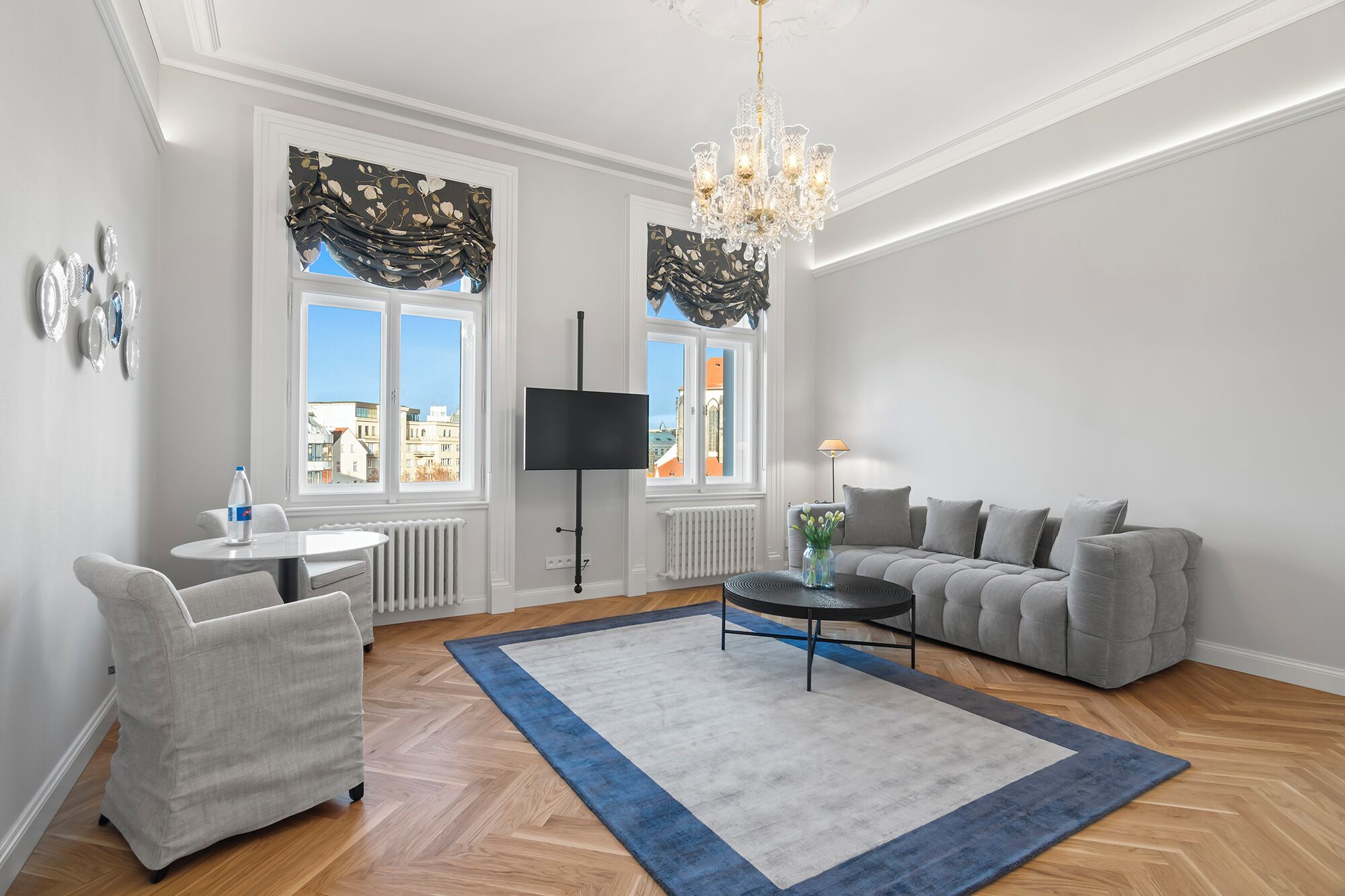 Un salon moderne avec un canapé, une table basse, un téléviseur et un lustre.
