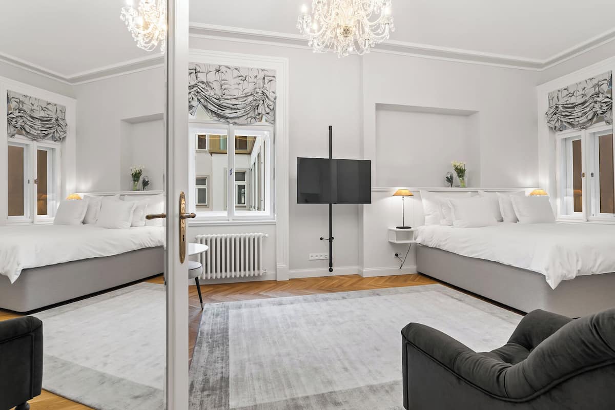 Une chambre moderne avec deux lits, un grand miroir, une télévision et un lustre.