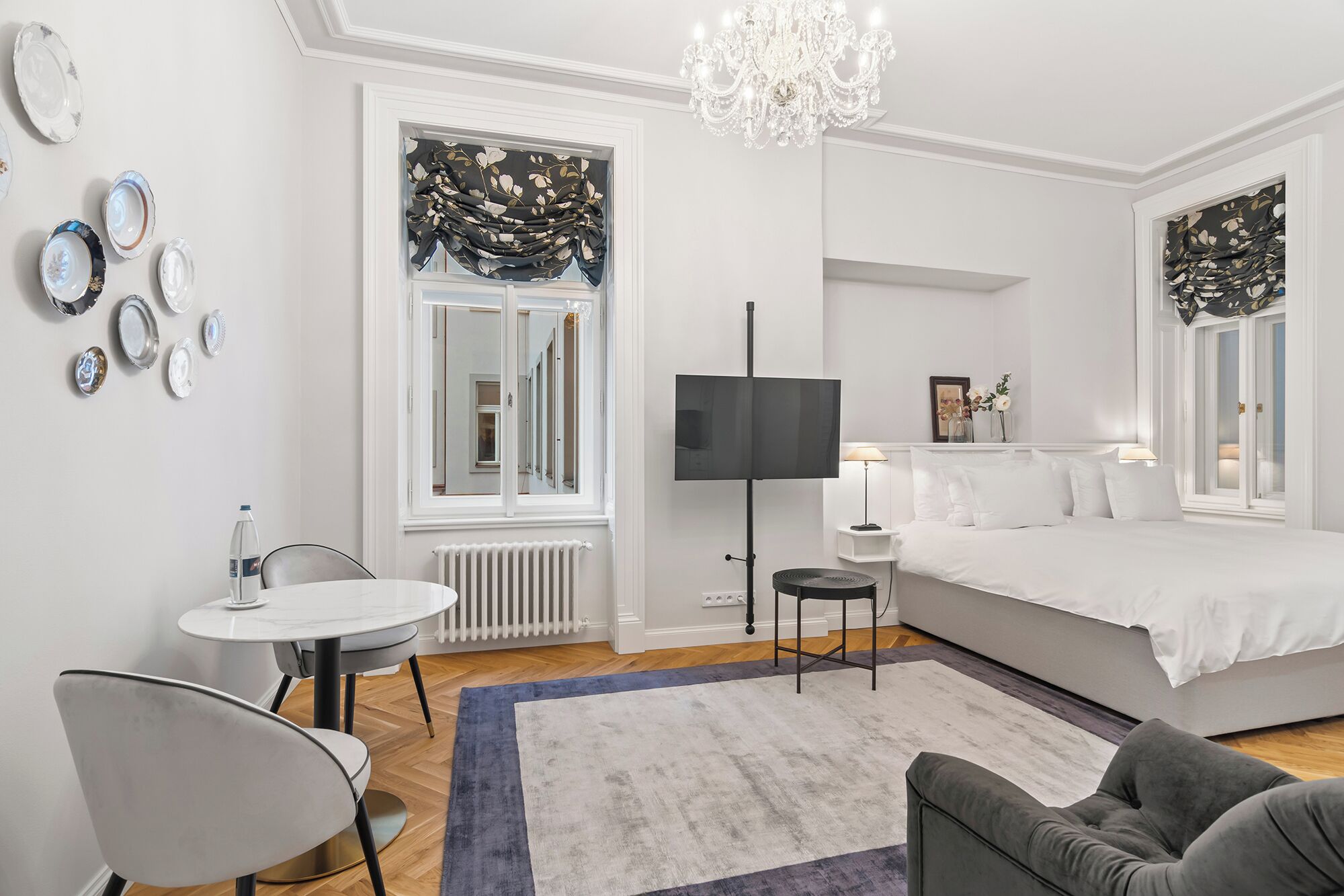 Quarto moderno com cama, escrivaninha, cadeira, televisão e pratos decorativos na parede.