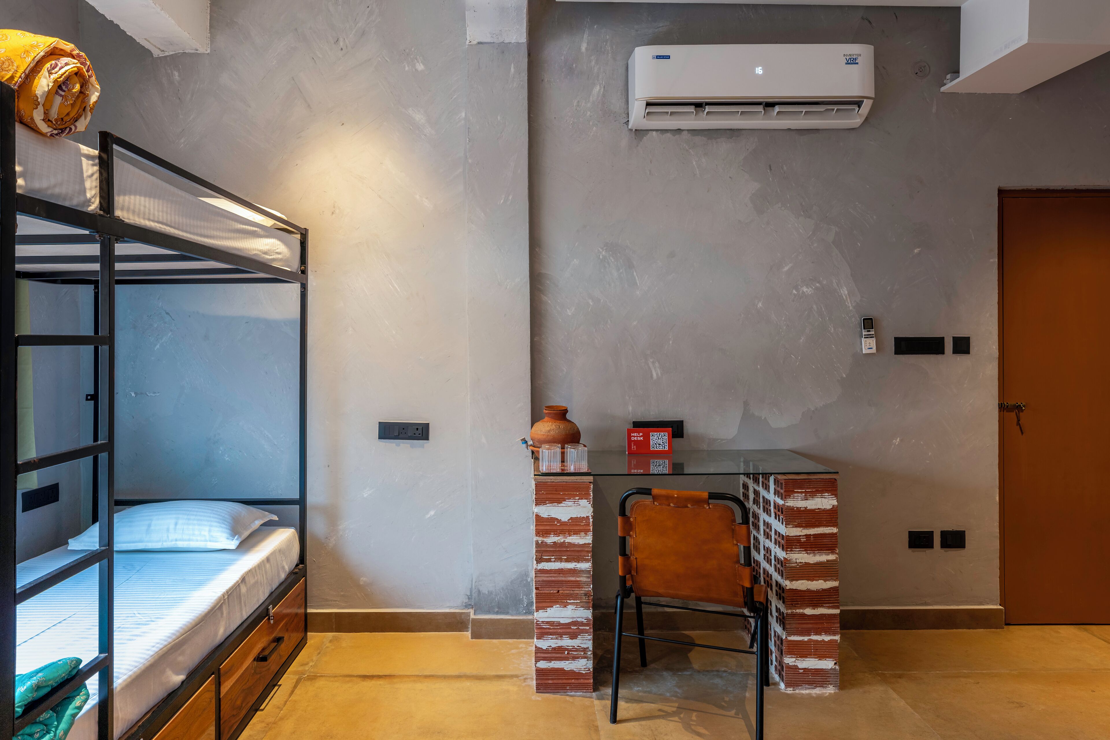 A bunk bed with a desk and chair, an air conditioner, and a door.