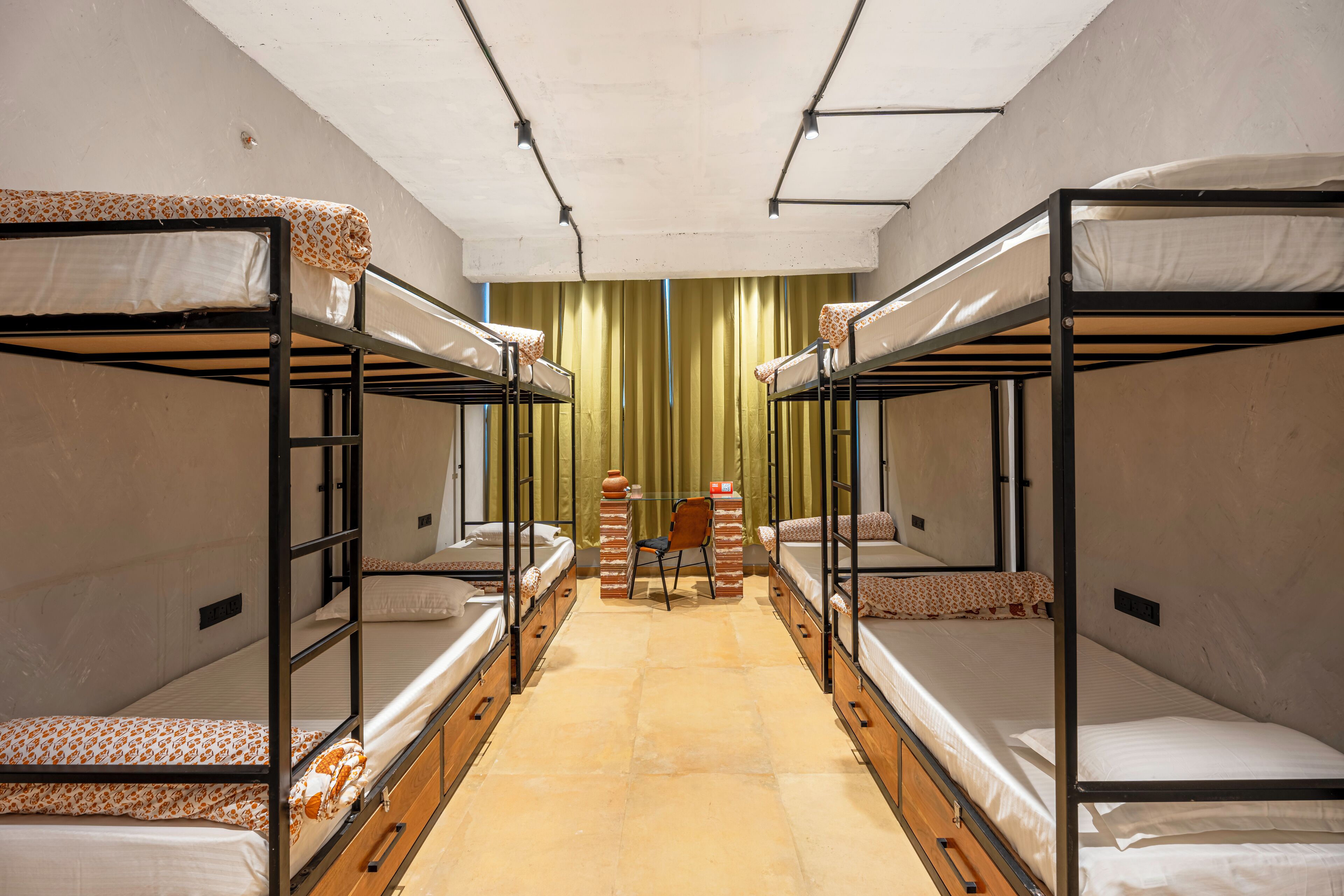 A dormitory room with bunk beds, a small desk, and a chair.