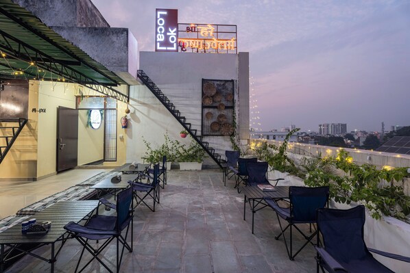 An outdoor seating area with tables and chairs, a staircase, and a view of the cityscape. - LOCAL LOK (Varanasi)